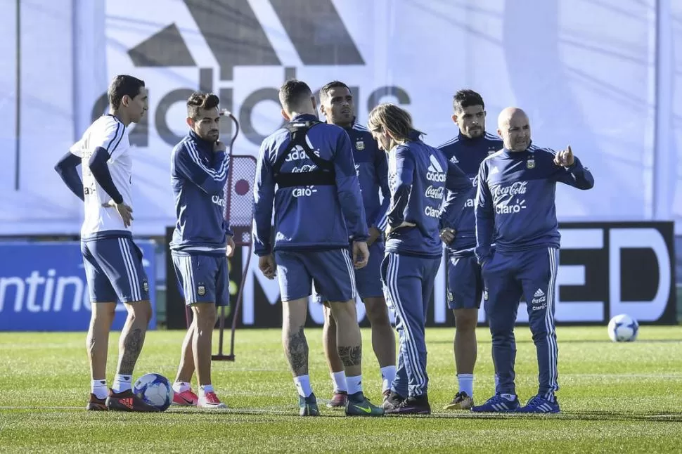 PRIMERA PRÁCTICA. Di María, Lautaro Acosta, Icardi (de espalda), Mercado, el ayudante de campo Beccacece y Ever Banega escuchan con atención a Sampaoli. telam