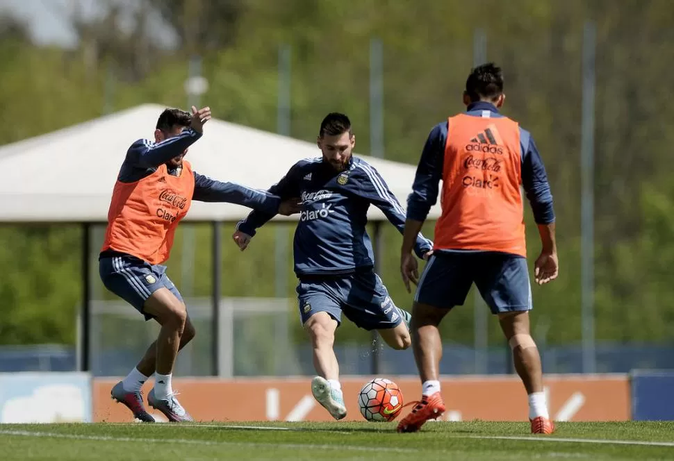 PUESTA A PUNTO EN EZEIZA. “La Pulga” Messi, que se entrenó junto a Benedetto, Acuña y “Papu” Gómez, remata ante la presión de dos rivales en la práctica. Dyn