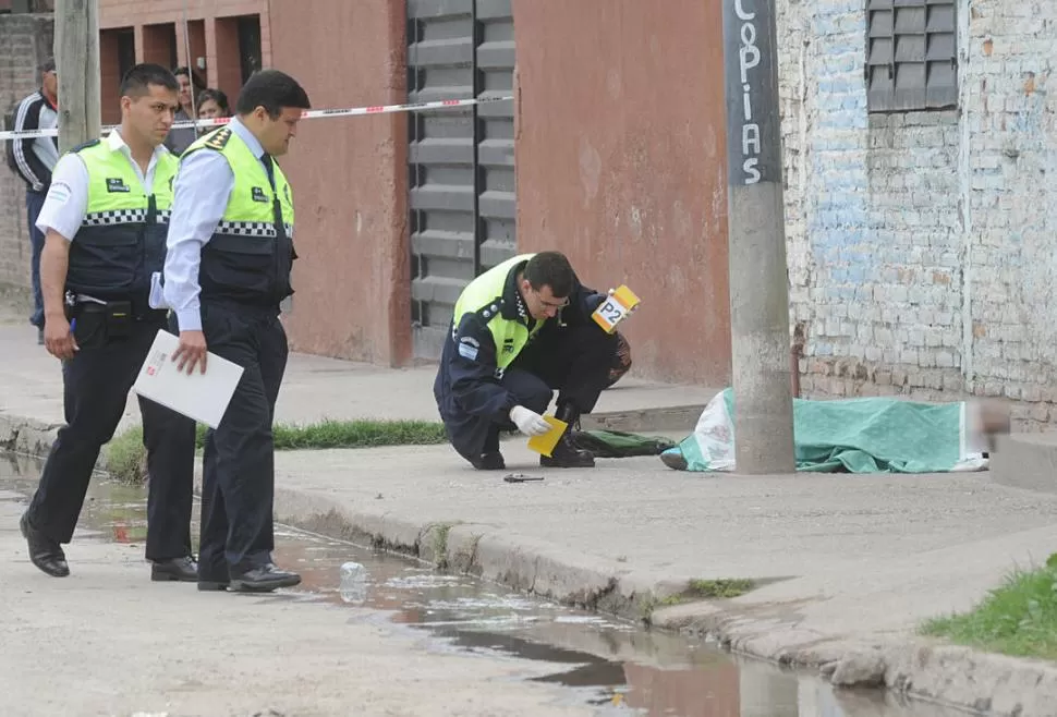 MUERTE EN LA AVENIDA SAN RAMÓN. El cuerpo del joven abatido quedó entre un poste y la pared de la fotocopiadora, cerca del revólver. la gaceta / foto de Antonio Ferroni