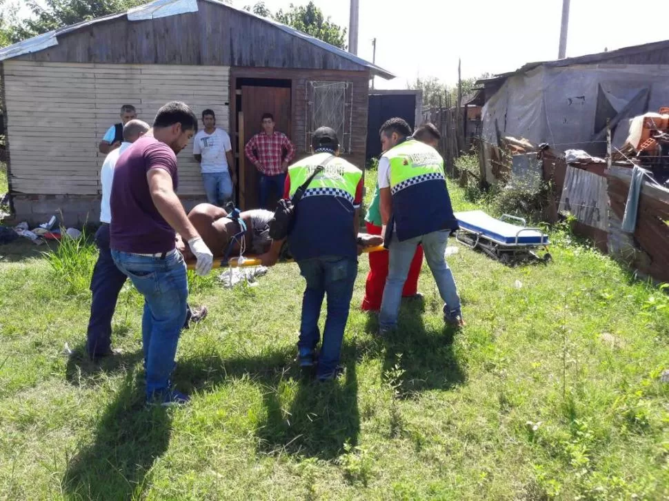 EN PLENA TAREA. Los policías trasladan en una camilla al asaltante herido.  