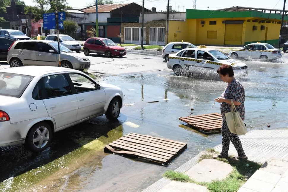 UNA LAGUNA. Trabajadores de una carnicería pusieron unos palets para que los vecinos puedan cruzar por la esquina de Bolivia y la avenida. LA GACETA / FOTOS DE ANALÍA JARAMILLO.- 