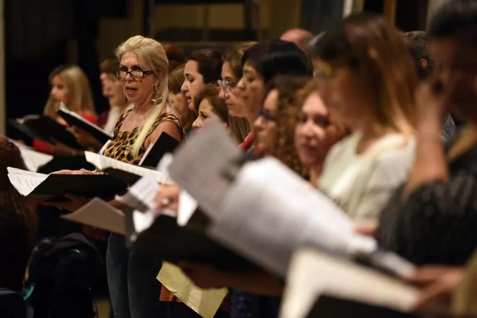 -TRABAJO Y PASIÓN. Las contraltos esperan su entrada mientras las sopranos acatan la partitura e interpretan lo que pide el director.-