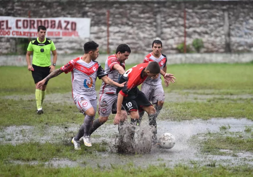 IMPOSIBLE JUGAR. En medio de un charco de agua, Sotomayor (10), de Amalia, trata de llevarse la pelota ante tres rivales. la gaceta / foto de Osvaldo Ripoll