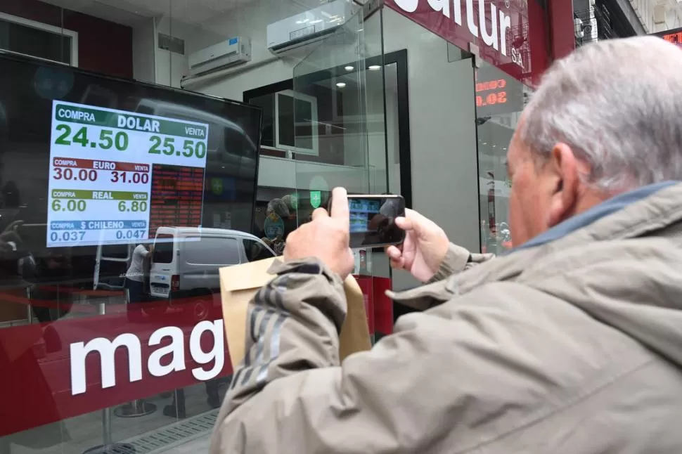 MERCADO RECALENTADO. Un transeúnte usa su celular para la foto, para mostrar luego que el valor de la moneda estadounidense “se disparó”. TELAM 