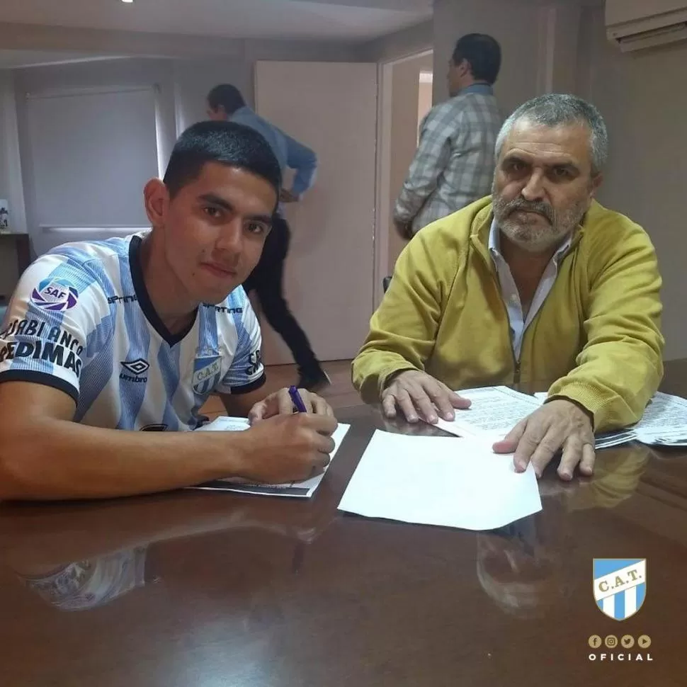 CON LA CAMISETA PUESTA. Tomás Rojas pone la firma en su contrato con Atlético ante la mirada de Mario Ávila, secretario del club. El volante se entrenará hoy.  twitter @ATOficial