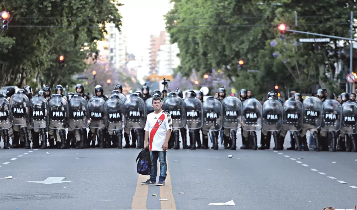 NO LO DEJEN SOLO. Este hincha parece buscar respuestas a lo sucedido con los policías de fondo. 