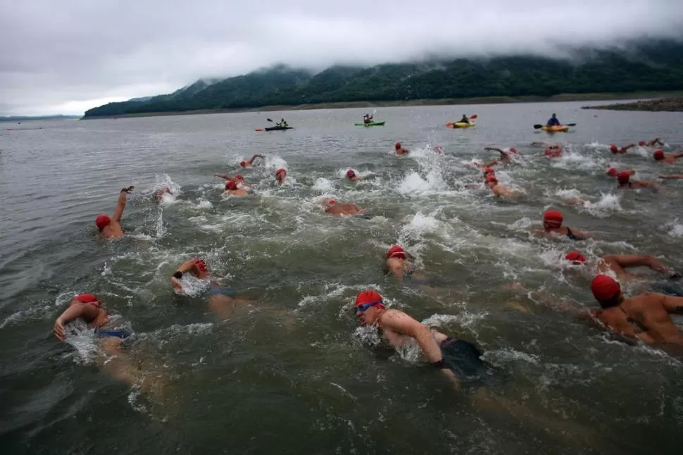 A LA CONQUISTA. El pelotón de nadadores se lanza hacia la inmensidad del dique custodiado por los kayaks de seguridad. El encanto del paisaje lo brindan los cerros. la gaceta / fotos de juan pablo sánchez noli