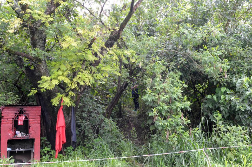 PERDIDO EN LA VEGETACIÓN. Un policía custodia el cuerpo, detrás de las banderas y de la gruta de El Gauchito Gil. la gaceta / fotos de franco vera