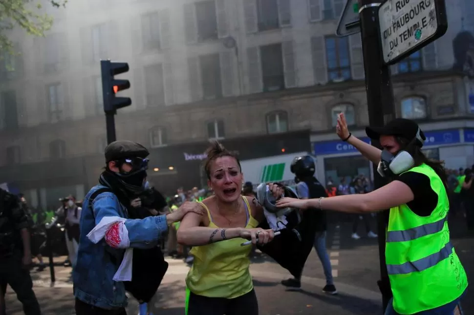 JORNADA DE RECLAMOS. Una manifestante trata de refugiarse de la represión, en el 23° sábado de protestas.  