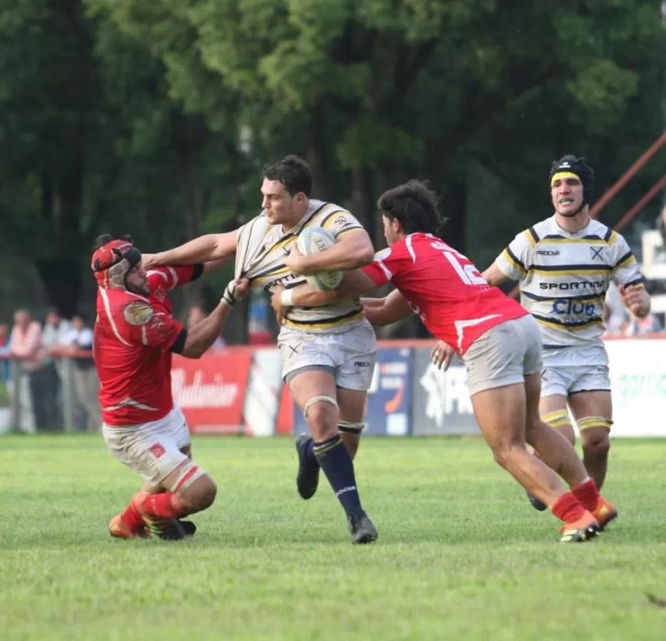 NO PUEDEN BAJARLO. José Calliera, con pelota atenazada y en otro ataque del “Benjamín”, buscar zafar del tackle de José Chico y del agarrón de Nicolás Casado. la gaceta / foto de juan pablo sanchez noli