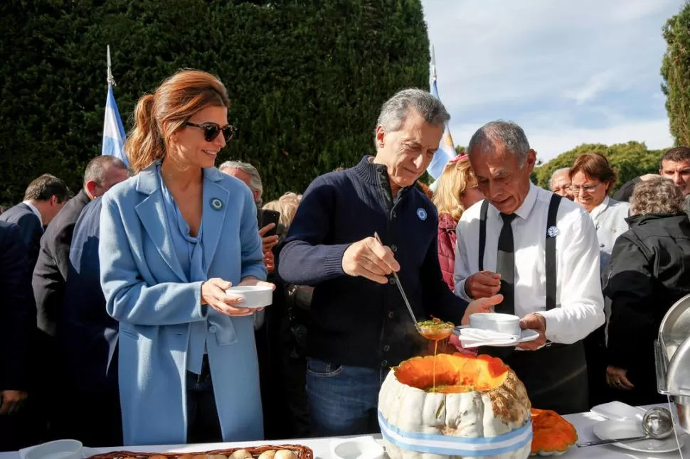 LOCRO EN OLIVOS. Macri sirve una cazuela, acompañado de su esposa. télam