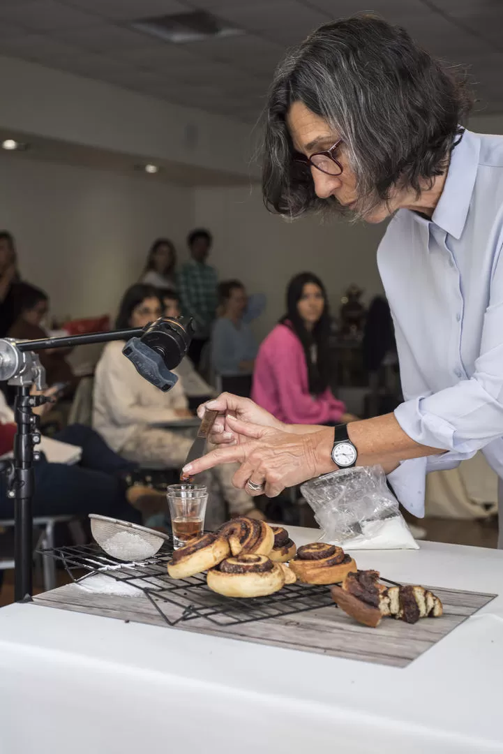 EL OFICIO. Marcela Lovegrove fotografía un plato frente a alumnos. 