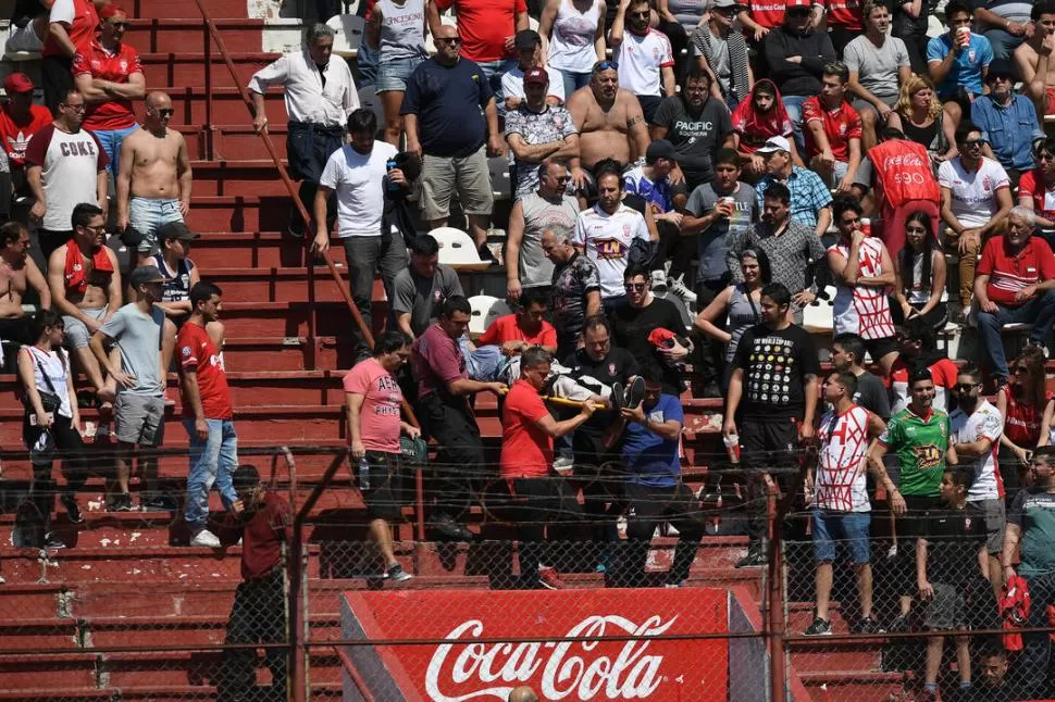 MOMENTO DE TENSIÓN. Personal de salud retira al hincha de Huracán que sufrió la descompensación en la tribuna de Huracán. El hombre murió horas después. 