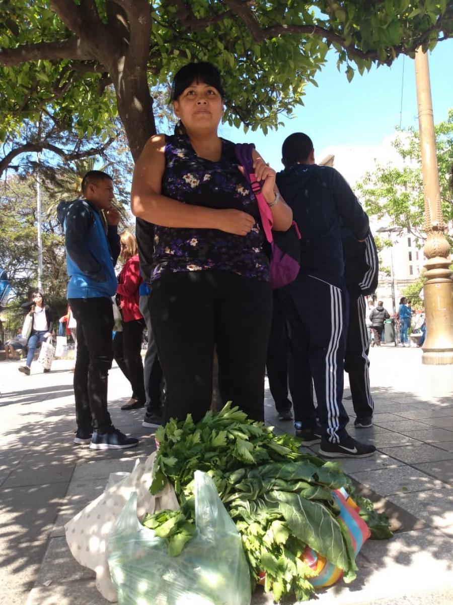 TAPÁNDOSE DEL SOL. Lorena Cortés, bajo un árbol y con sus compras