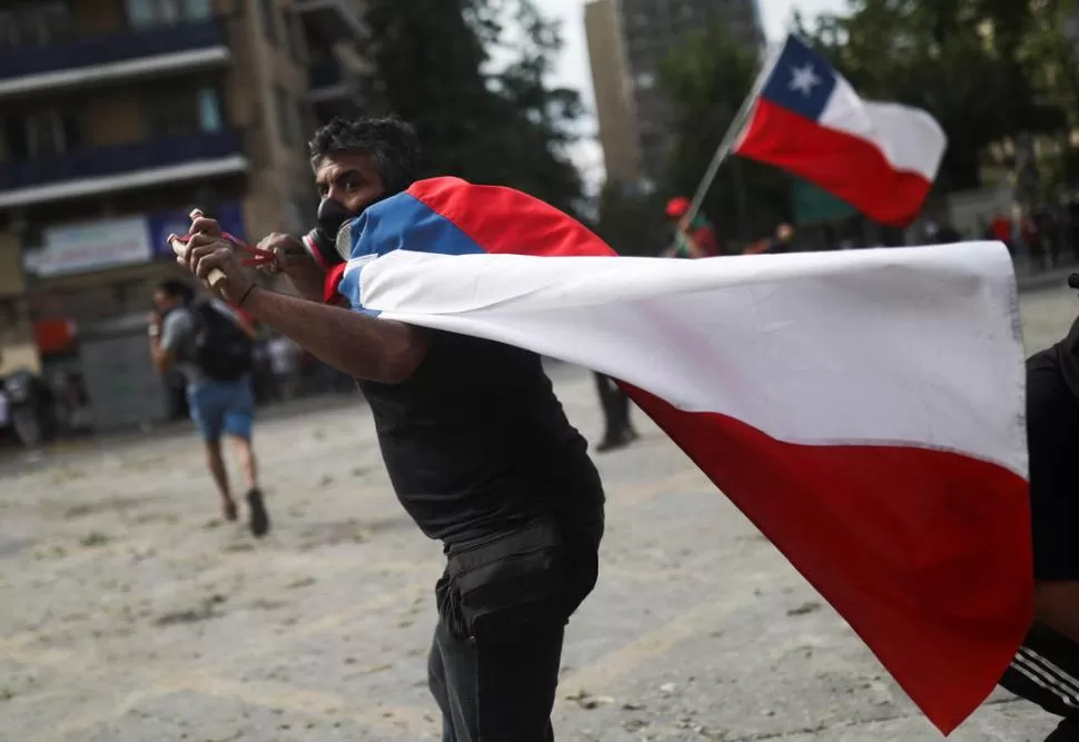 POR LA FUERZA. En las calles, los manifestantes enfrentan a los militares y carabineros con hondas y piedras. reuters 