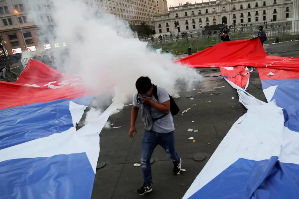 CONTRA EL MODELO ECONÓMICO. Un manifestante intenta caminar en medio de gases lacrimógenos, fuera del Palacio Presidencial de La Moneda.  reuters 