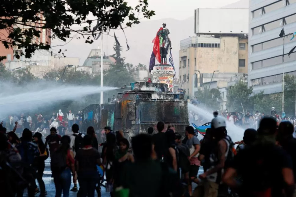 ENFRENTAMIENTO. Un camión hidrante busca dispersar la protesta.  