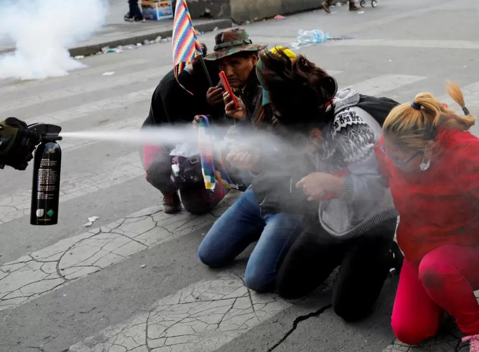 CHOQUES. Un efectivo de las fuerzas de seguridad rocía con gas pimienta a los manifestantes en la ciudad de Sacaba, Cochabamba. Reuters