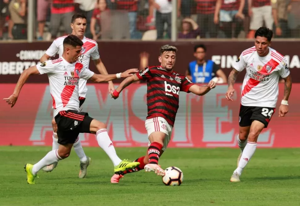 INTENSA MARCA. El uruguayo Giorgian De Arrascaeta se lleva la pelota ante la presión del tucumano Exequiel Palacios y de Enzo Pérez, mientras “Nacho” Fernández lo sigue desde atrás. reuters