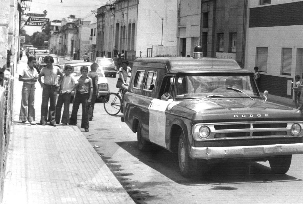 HISTORIA. Curiosos miran un móvil policial en el lugar donde se perpetró el criminal atentado contra la familia Viola.