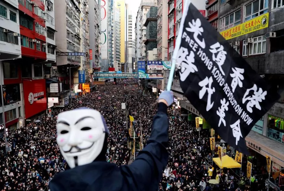 CON LA MÁSCARA DE GUY FAWKES. Un militante ondea una bandera durante la marcha del Día de los Derechos Humanos, en Hong Kong. 