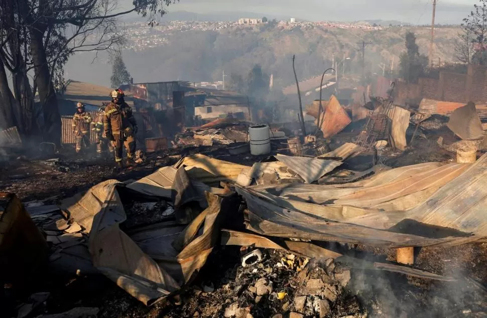 DESTRUCCIÓN. Los bomberos recorren las zonas cercanas a los cerros Rocuant y San Roque, donde 150 casas resultaron devastadas por el fuego. fotos reuters
