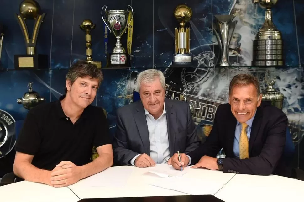 DE VUELTA A CASA AMARILLA. Miguel Ángel Russo estampa la firma el contrato que lo ligará al club por los próximos 12 meses. Junto a él, Jorge Ameal y Mario Pergolini. prensa boca juniors