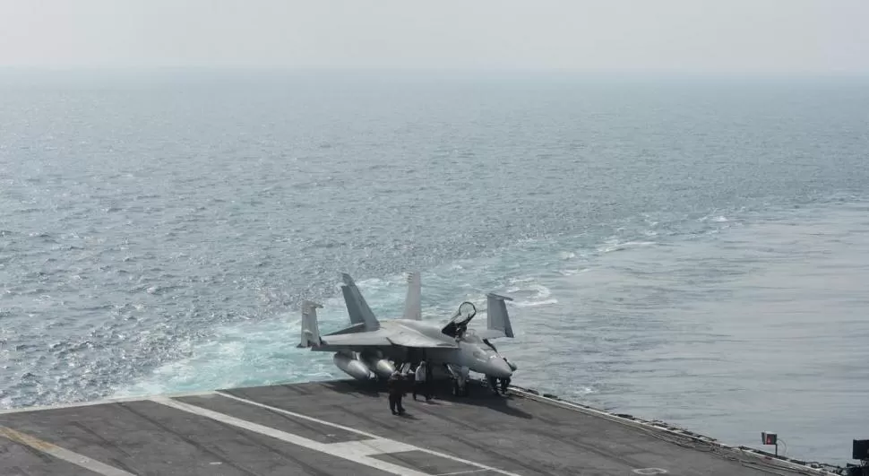 REVISIONES MECÁNICAS. Un grupo de técnicos supervisa al F18 Super Hornet en un extremo de la plataforma del buque. 