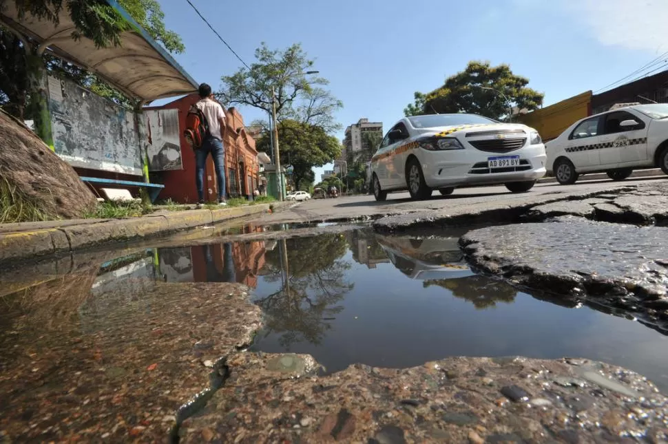 ROTURAS. Mientras una persona espera el colectivo en barrio Piedrabuena, los líquidos cloacales afloran sobre el pavimento. FOTO / Archivo LA GACETA 