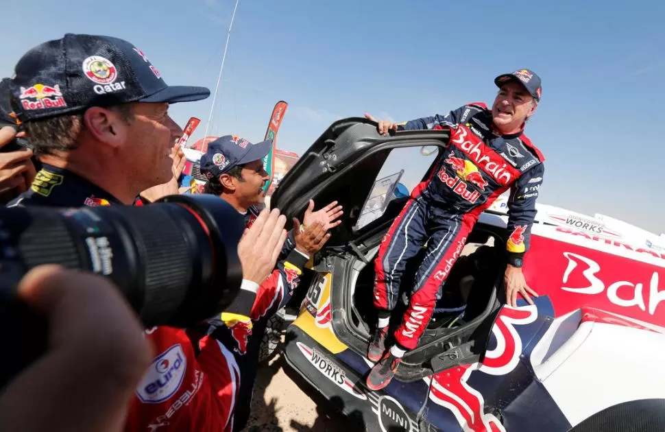 “EL MATADOR” INALCANZABLE. Carlos Sainz emerge triunfal de su Mini tras conquistar su tercer título dakariano en Autos. Nasser Al Attiyah lo aplaude, luego de haber hecho lo posible por darle alcance. fotos reuters