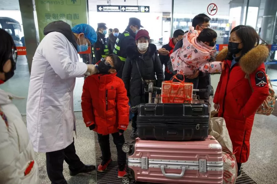 CONTROLES EN LOS AEROPUERTOS. Un médico le toma la temperatura a un chico en el aeropuerto de la provincia china de Hunan. Reuters