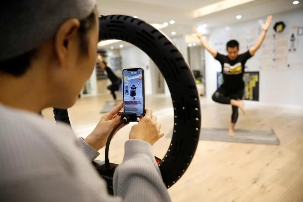 DISTANCIA. La entrenadora Liu Xiaojin transmite clases por internet, para evitar contagios en el gimnasio.   reuters 