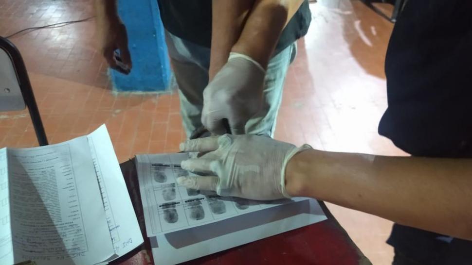 “PIANITO”. Un policía le pinta los dedos a uno de los aprehendidos.  
