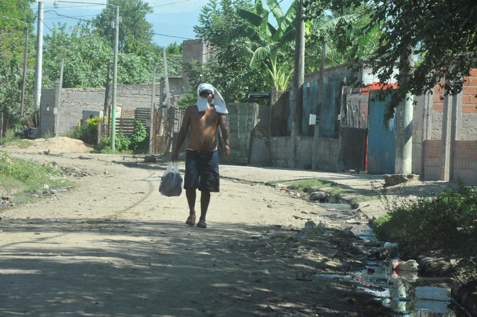 ENTRE EL CALOR Y EL CORONAVIRUS. Un joven del barrio fue al almacén y se cubrió la cabeza con su remera.