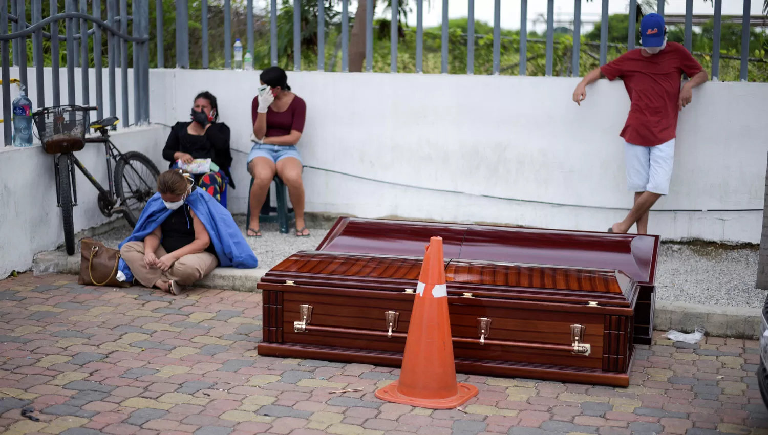 DESESPERADOS. Familiares esperan con sus cajones en el estacionamiento del hospital Guasmo Sur, de Guayaquil.