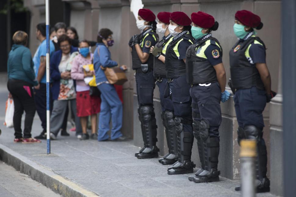 PATRULLA. Un pequeño grupo de cinco policías hace guardia afuera de banco. Detrás, los beneficiarios.