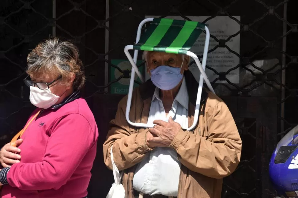 PACIENCIA. Dos jubilados en una de las colas para ingresar a los bancos. Él previó la espera y llevó una silla. 