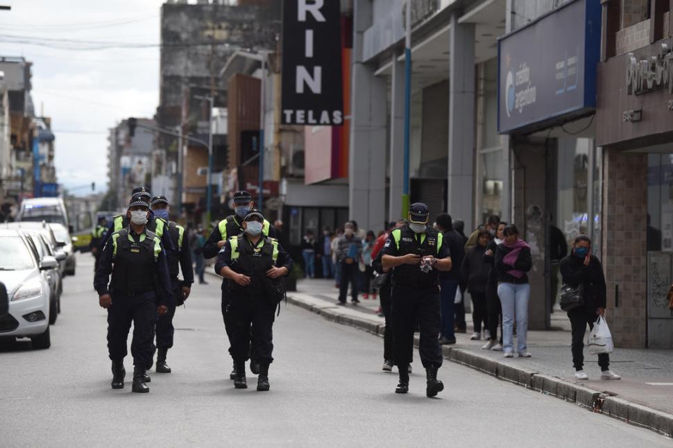 CONTROLES. Un grupo de policías patrulla el microcentro; de fondo, la gente hace cola para pagar cuentas.