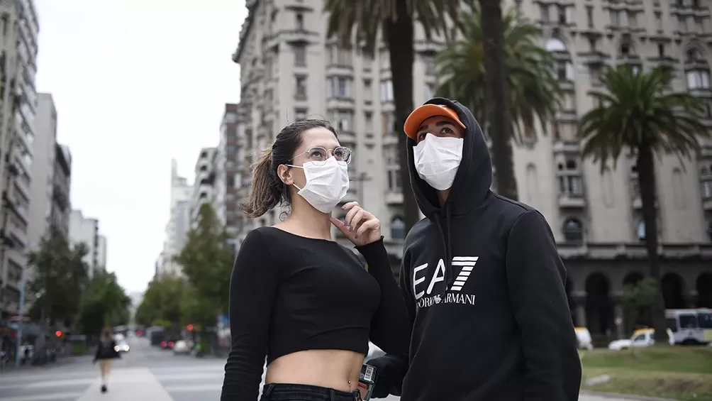 EN BUENOS AIRES. Una pareja pasa con sus respectivos barbijos en una calle desolada de la Ciudad. TÉLAM