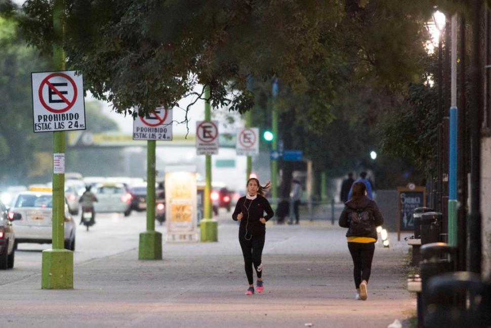 ASÍ SÍ. Una mujer corre con el barbijo en el cuello. No debe usárselo para correr pero sí para trasladarse.