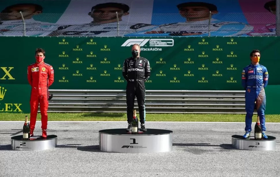 UNA IMAGEN INÉDITA. El francés Charles Leclerc (2°); el finlandés Valtteri Bottas (1°) y joven británico de sólo 20 años, Lando Norris (3°), con tapabocas y sobre un podio minimalista, en el asfalto del Red Bull Ring. reuters 