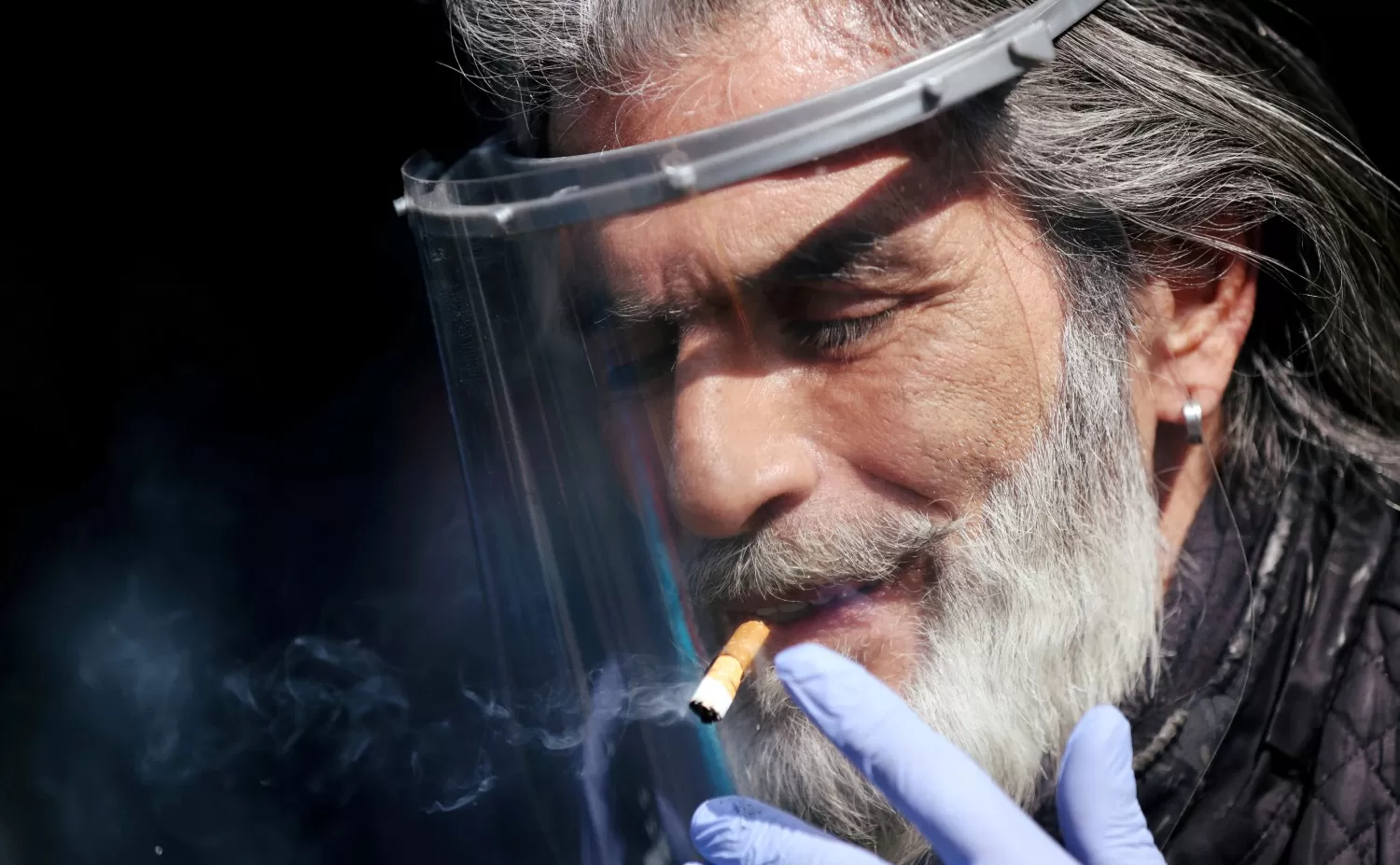PANDEMIA. Un hombre fuma con una mascarilla.