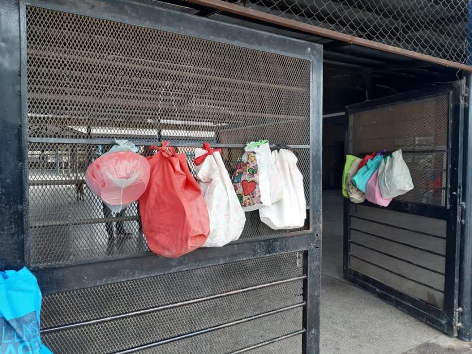 DISTANCIA SOCIAL. Las madres dejan atados a la reja de la escuela bolsas con táperes para retirar las viandas del comedor. la gaceta / foto de martín dzienczarskI