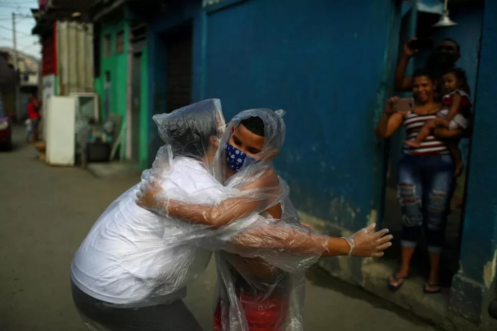 RÍO DE JANEIRO. La maestra Maura Silva, creadora del “kit del abrazo” (un sistema de protección precario contra el coronavirus hecho con bolsas) se despide de su alumno Yuri Araujo  