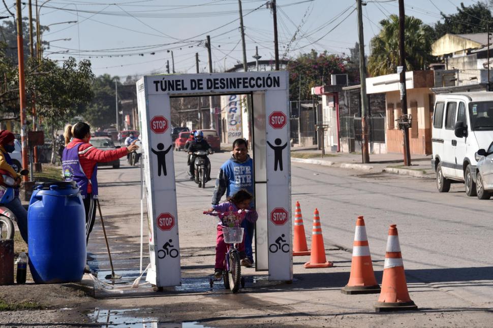 SANITIZANTE. Vecinos pasan por el túnel instalado para desinfección.