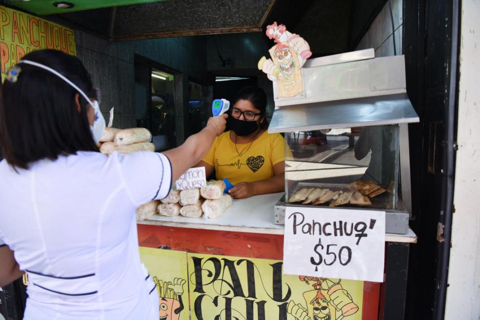 EN LOS COMERCIOS. Agentes toman la temperatura a una empleada. 