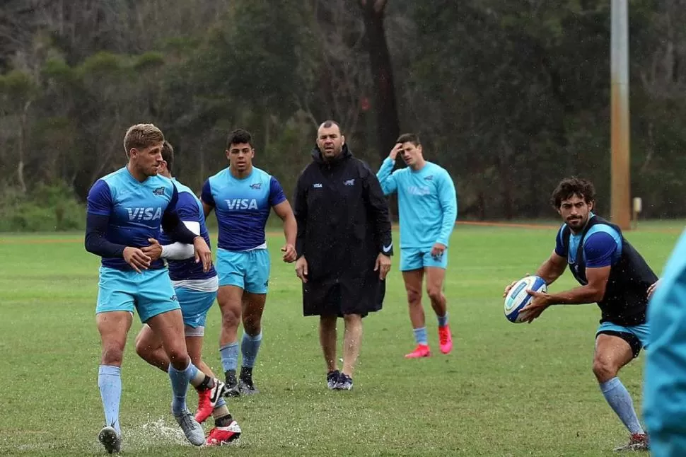 OBSERVACIÓN. Felipe Ezcurra con la pelota, seguido por el tucumano Miotti y la mirada de Cheika.  