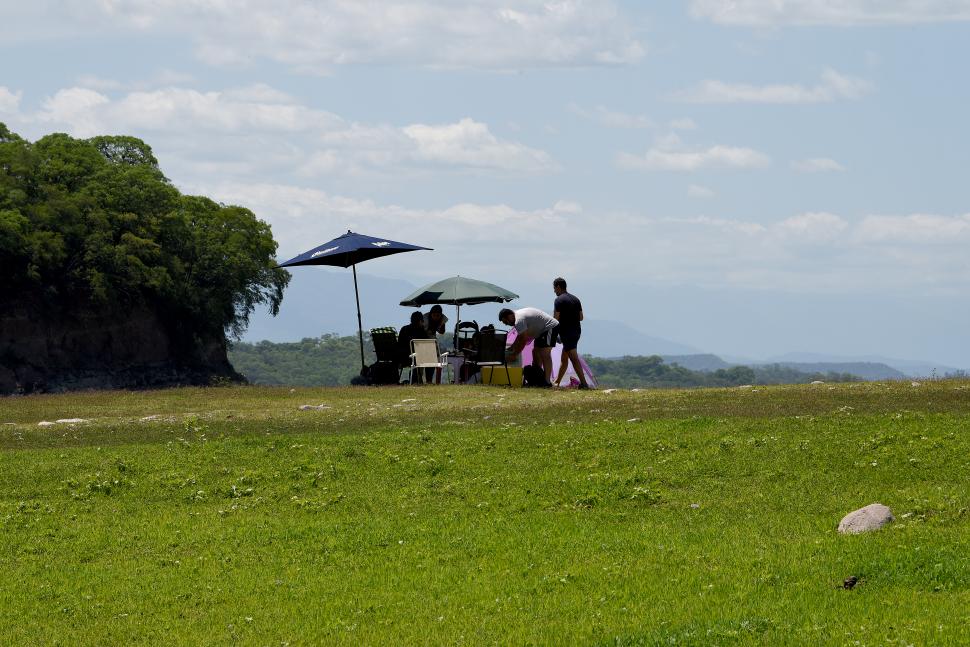 DE PICNIC. Protegiéndose con sombrillas, pasando un buen momento.  