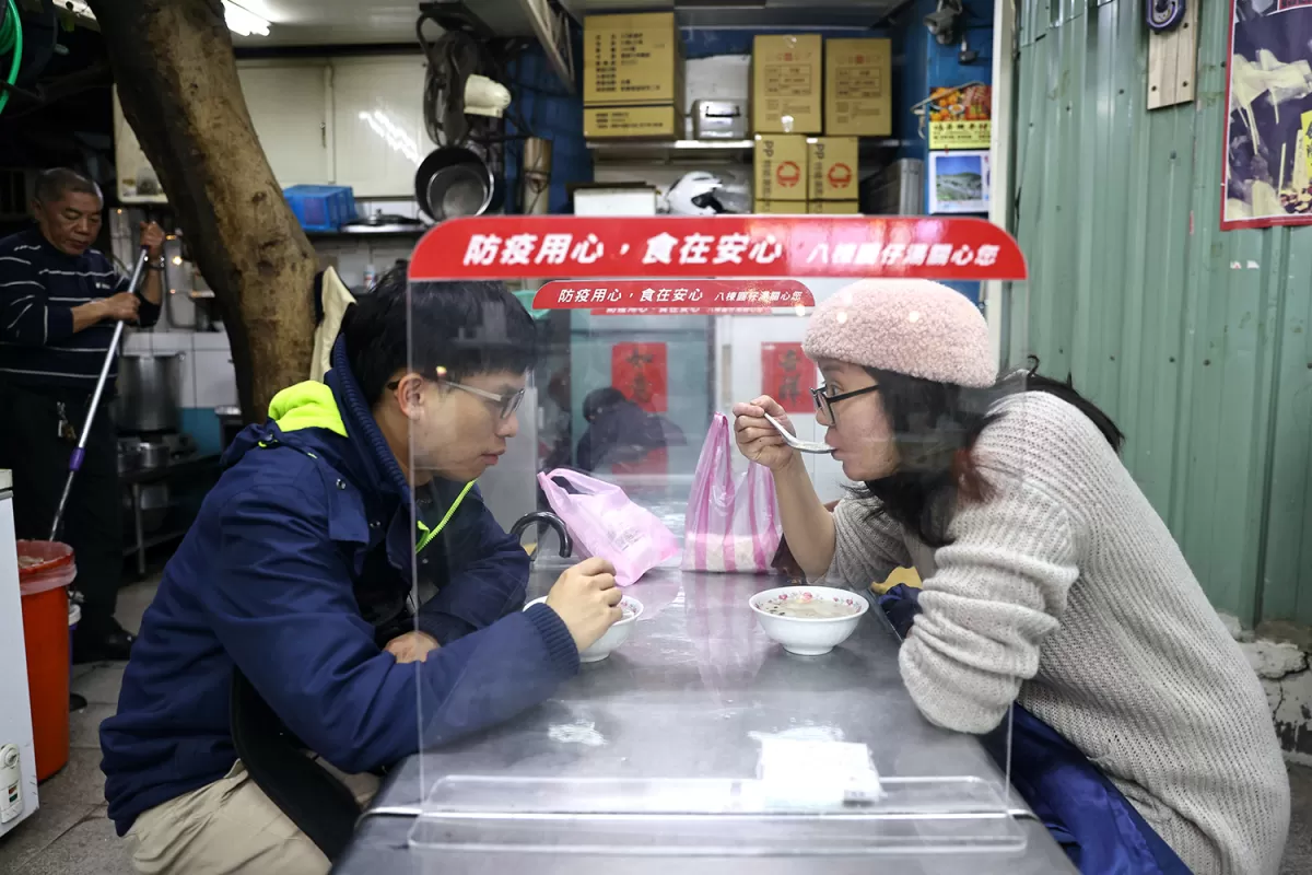 NUEVAS MANERAS. La pandemia del nuevo coronavirus obligó a cambiar las formas en que se desarrollan actividades cotidianas, como esta pareja que almuerza en el mercado céntrico de Taipei, en Taiwan, separados del resto de clientes por mamparas plásticas, para evitar contagios. 