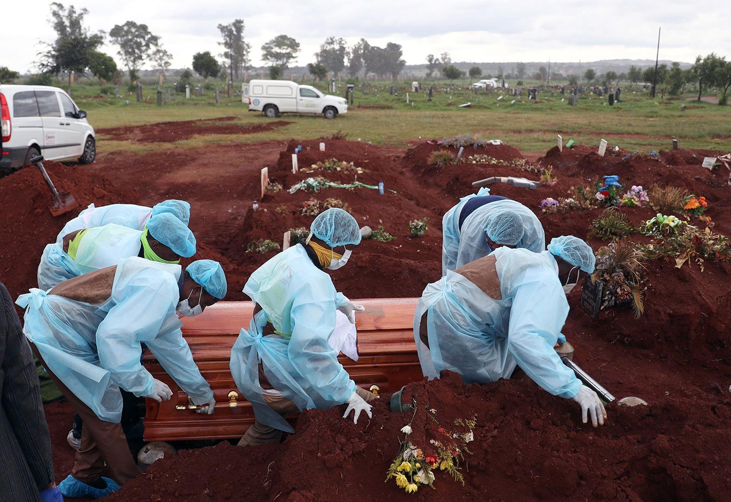 CUARENTENA NACIONAL. Funebreros entierran el cajón de una víctima de covid-19, en Olifantsvlei, Sudáfrica, un país que volvió al confinamiento estricto luego de que se dispararon los contagios.